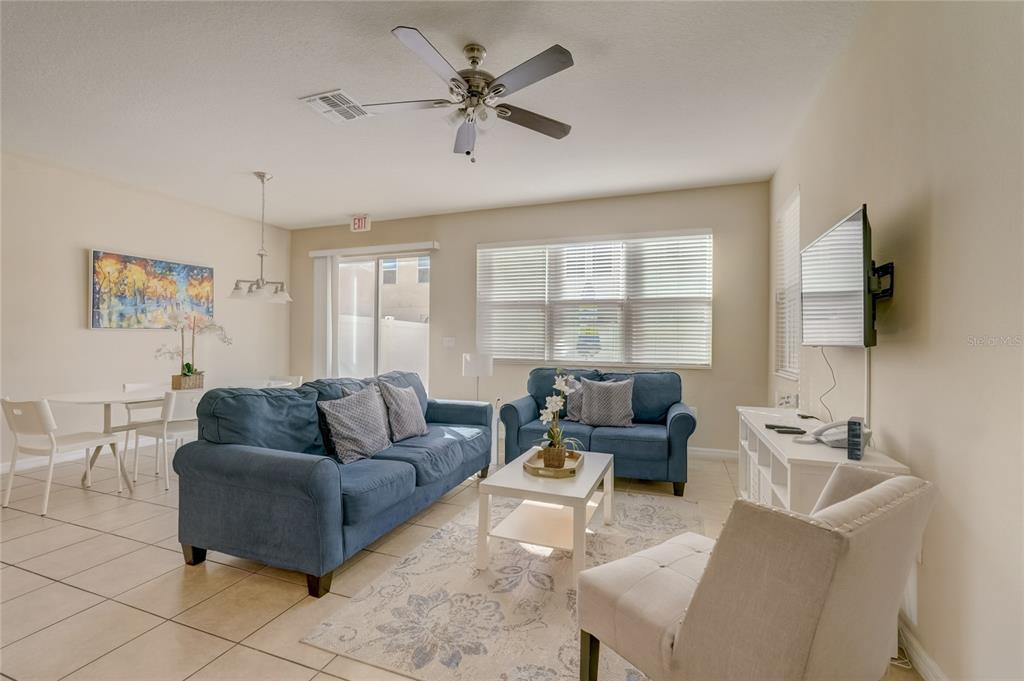 A living room with blue sofas, a white coffee table, and a dining area nearby — 5126 ADELAIDE DRIVE, KISSIMMEE, FL