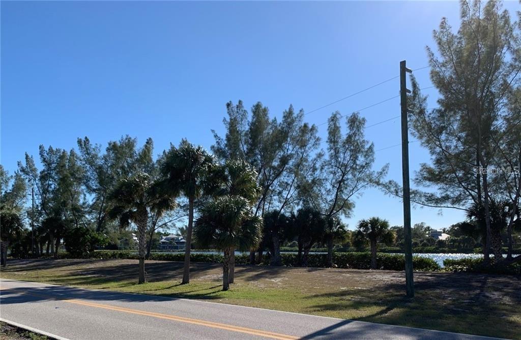 A paved road runs alongside a grassy lot with palm trees and a water view — 16080 GULF SHORES DRIVE, BOCA GRANDE, FL