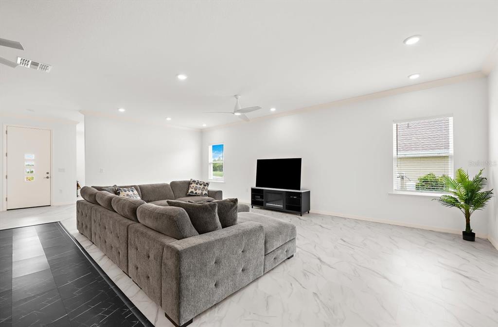 A living room features a large gray sectional sofa, a television console, and marble-look flooring — 2365 MAURITANIA ROAD, PUNTA GORDA, FL