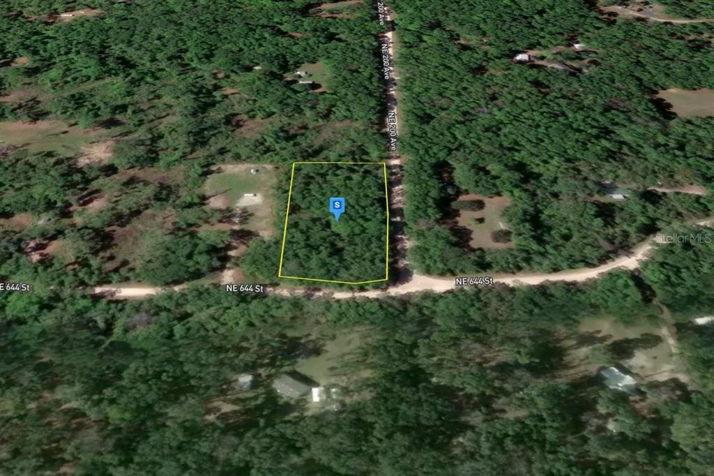 An aerial view shows a rectangular, tree-covered vacant lot outlined in yellow near a road — 1200 NE 644TH STREET, OLD TOWN, FL