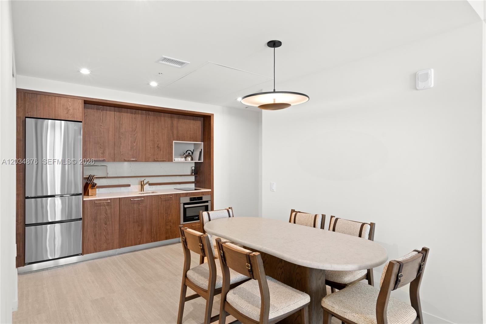 A modern kitchen with wood cabinetry and stainless steel appliances sits beside a dining area — 1611 SW 2nd Ave # 816, Miami FL 33129, MIAMI, FL