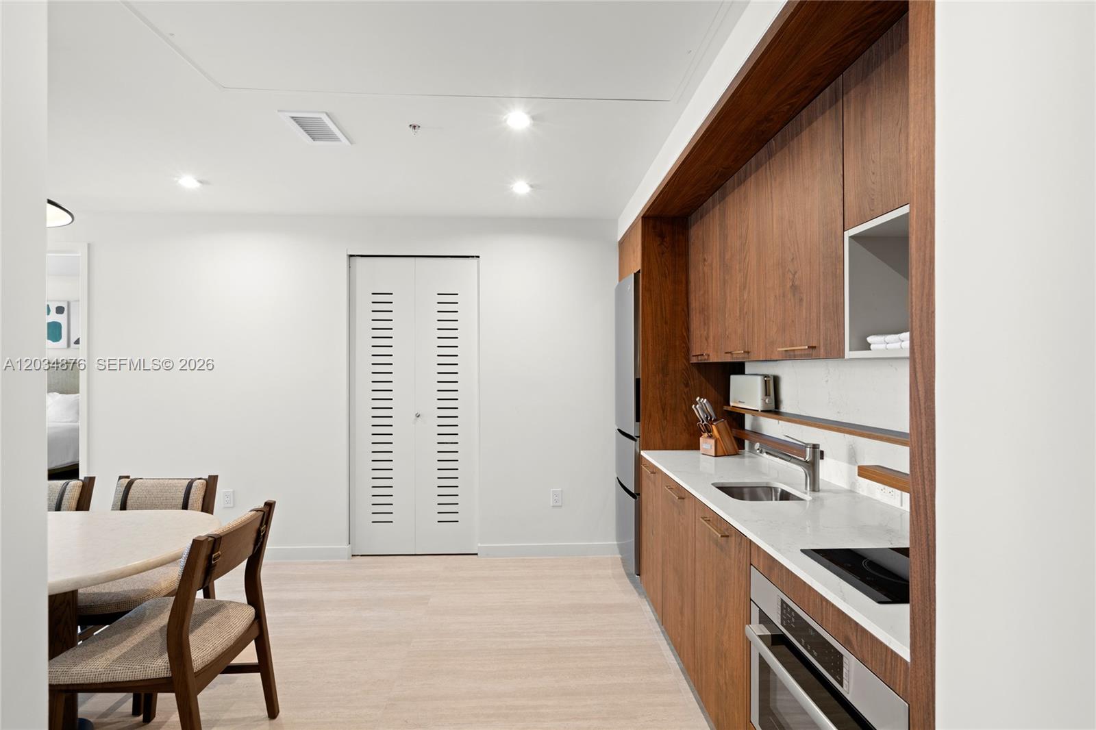 A kitchen with wood cabinetry and white countertops sits adjacent to a dining area — 1611 SW 2nd Ave # 816, Miami FL 33129, MIAMI, FL