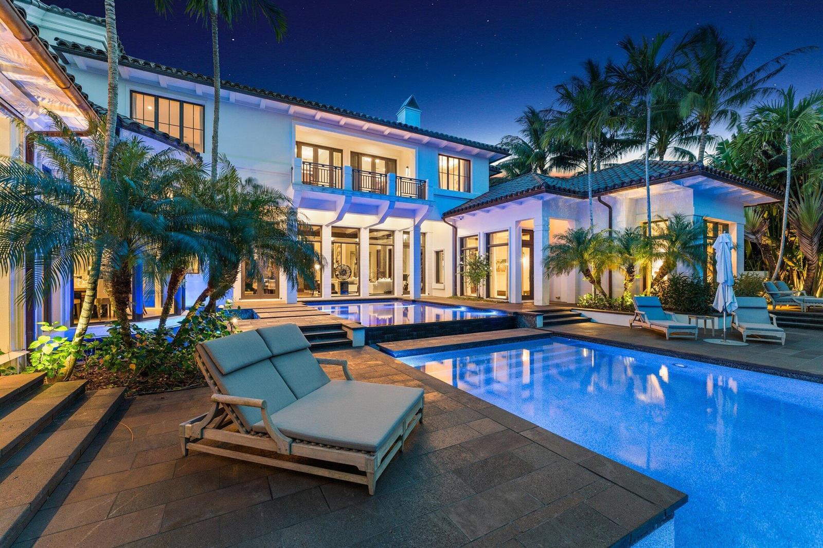 A two-story luxury home with a swimming pool, lounge chairs, and palm trees at night — 232 Bears Club Drive, Jupiter FL 33477, JUPITER, FL