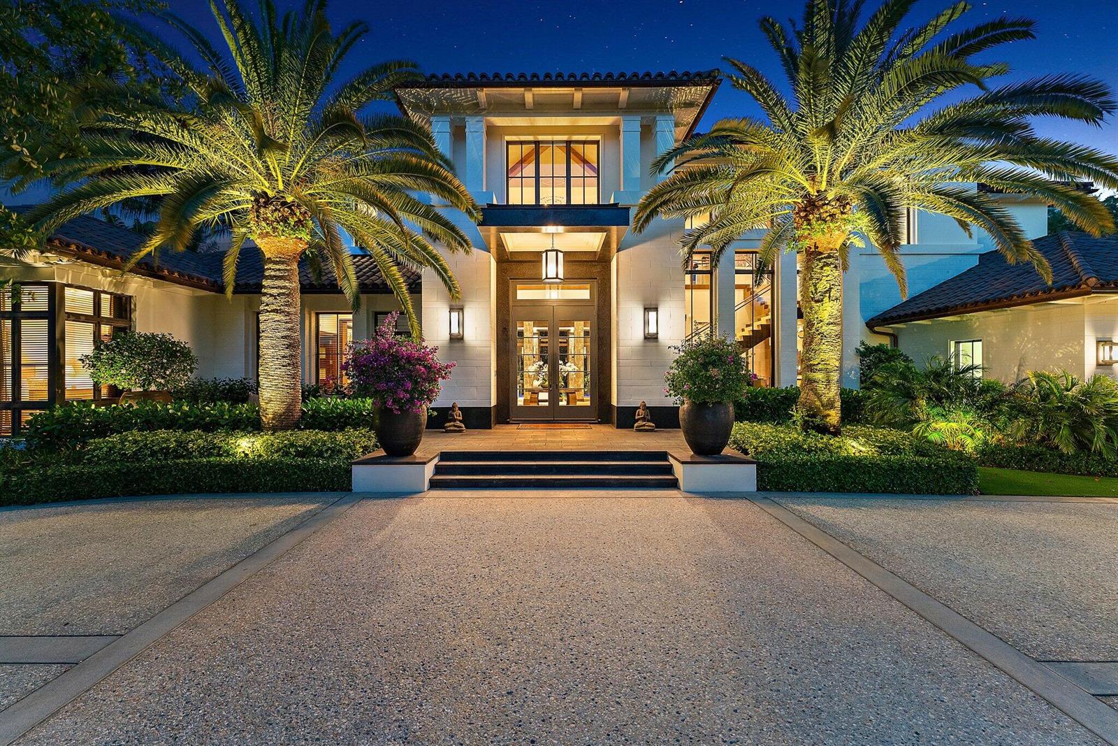 A modern Mediterranean-style house exterior at night with palm trees and a paved driveway — 232 Bears Club Drive, Jupiter FL 33477, JUPITER, FL