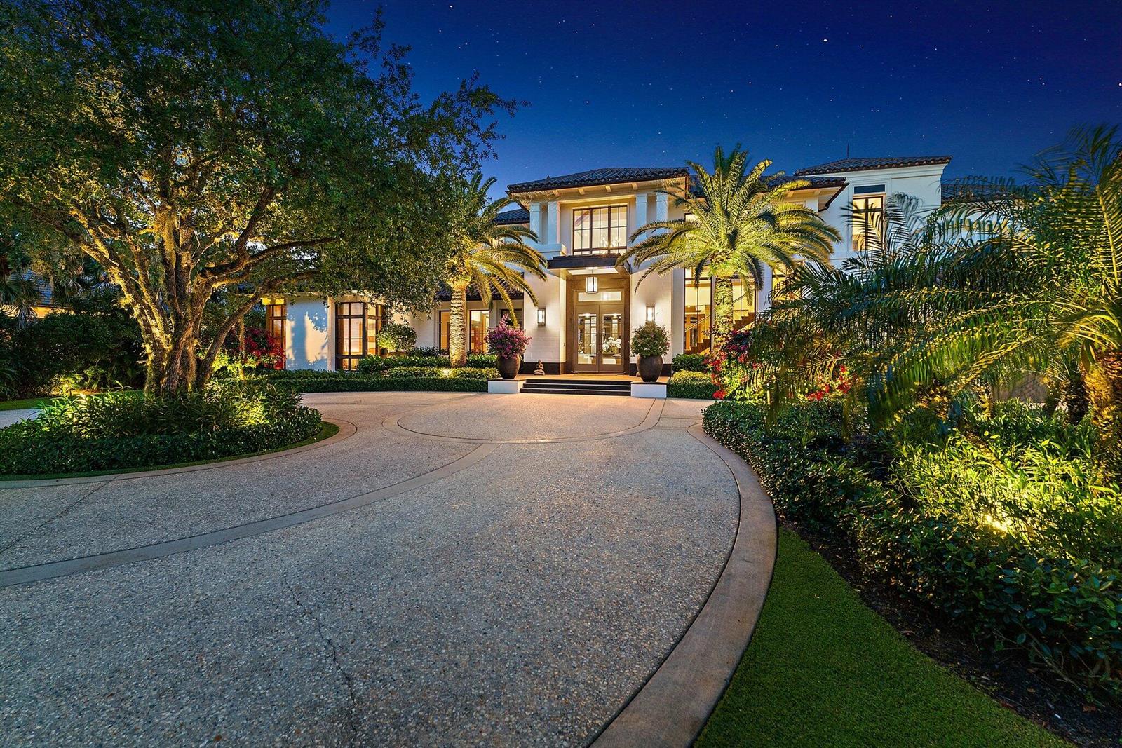 A large two-story white house with a circular driveway and palm trees at night — 232 Bears Club Drive, Jupiter FL 33477, JUPITER, FL