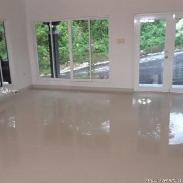 An empty room with light-colored tile flooring, large windows, and glass doors looking outside — 1 Sanctuary At Farm Hill Jamaic, JM JMCAN19, JM