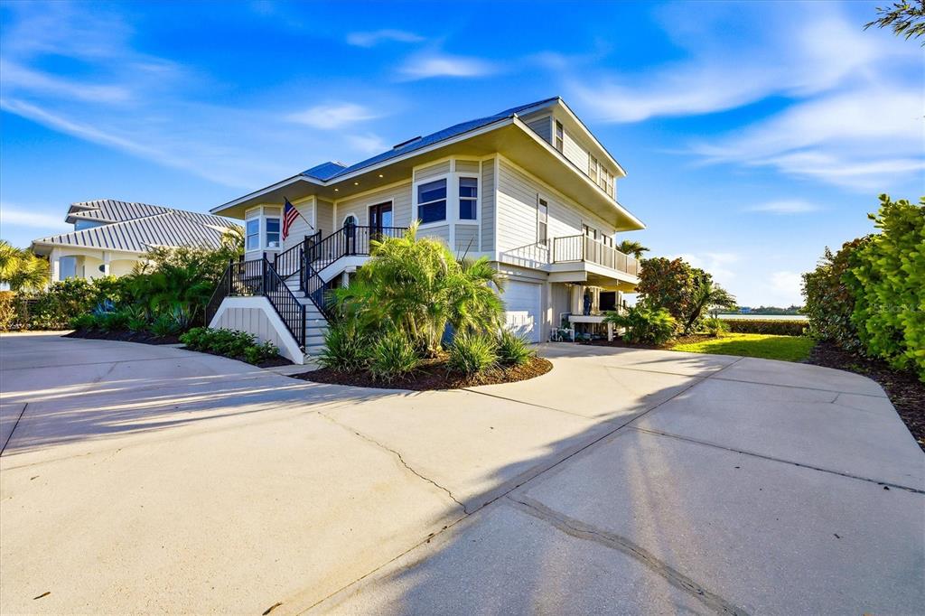 A two-story house with a concrete driveway, elevated entrance stairs, and a garage underneath — 9941 EAGLE PRESERVE DRIVE, ENGLEWOOD, FL
