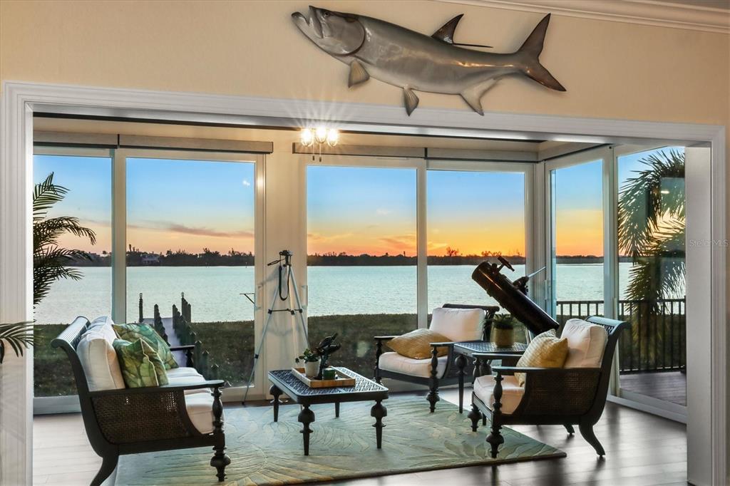 A sunroom with a large fish wall sculpture, telescope, and floor-to-ceiling windows overlooking water — 9941 EAGLE PRESERVE DRIVE, ENGLEWOOD, FL