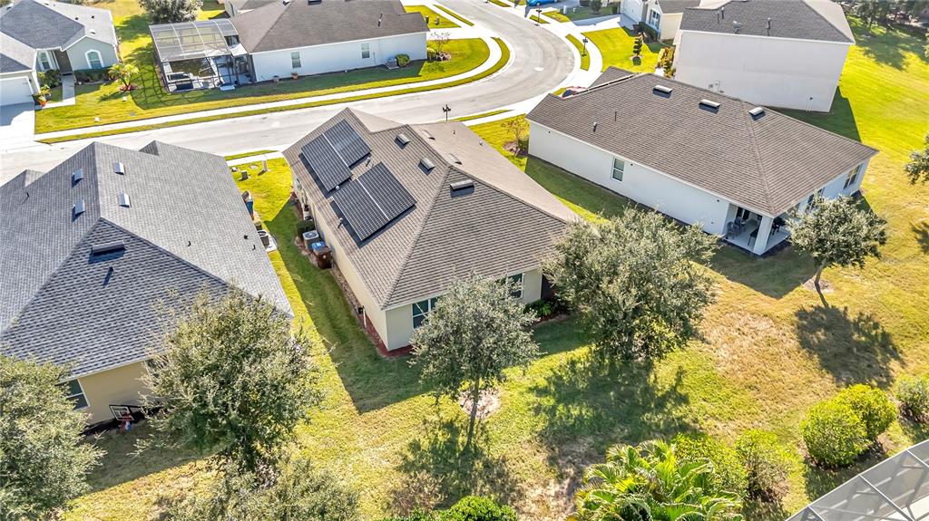 An aerial view shows three suburban houses with dark shingled roofs and a solar array — 849 SHEEN CIRCLE, HAINES CITY, FL