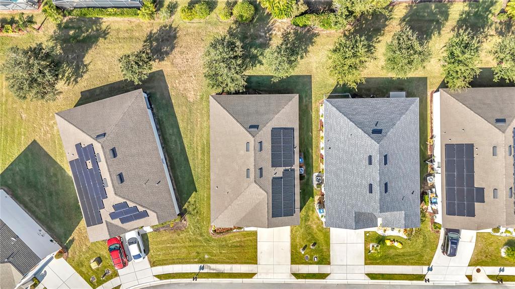 An aerial view shows four suburban houses with solar panels on their roofs — 849 SHEEN CIRCLE, HAINES CITY, FL