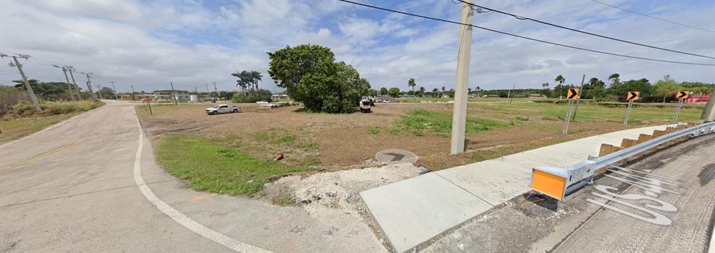 A vacant, grassy corner lot sits at the intersection of a paved road and highway — RARDIN AVENUE, PAHOKEE, FL