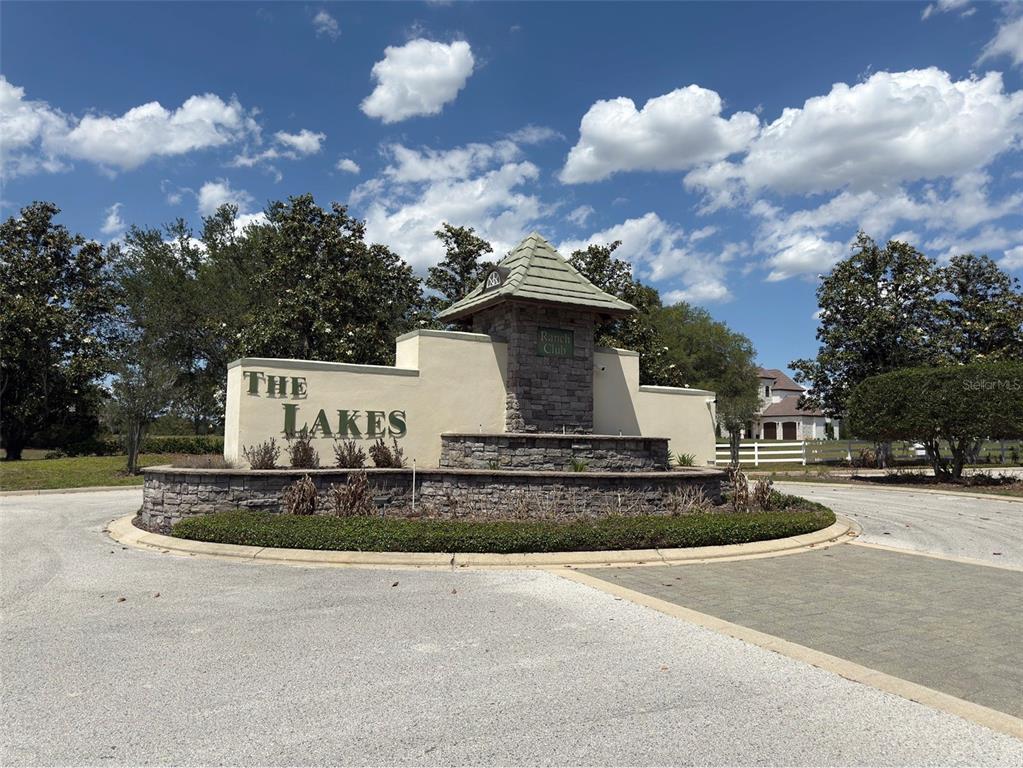 A stone and stucco entrance sign for The Lakes community sits in a traffic circle — 6115 RANCH LAKE ROAD, GROVELAND, FL