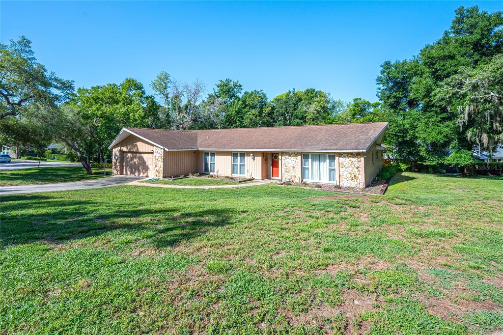 A single-story ranch-style house with a stone facade, wood siding, and a large front lawn — 800 SWEETWATER CREEK COURT, LONGWOOD, FL