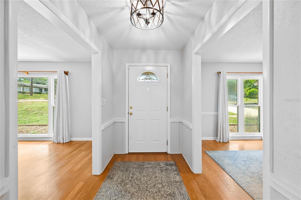 A bright entryway features a white front door, hardwood floors, and two adjacent living spaces — 800 SWEETWATER CREEK COURT, LONGWOOD, FL