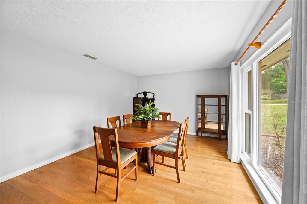 A dining room features a wooden table, chairs, a display cabinet, and a large window — 800 SWEETWATER CREEK COURT, LONGWOOD, FL