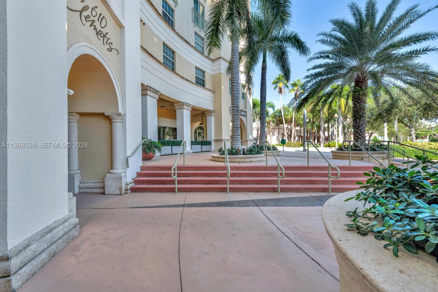 Exterior view of a building entrance with steps, palm trees, and a concrete walkway — 610 Clematis St # 406, West Palm Beach FL 33401, WEST PALM BEACH, FL