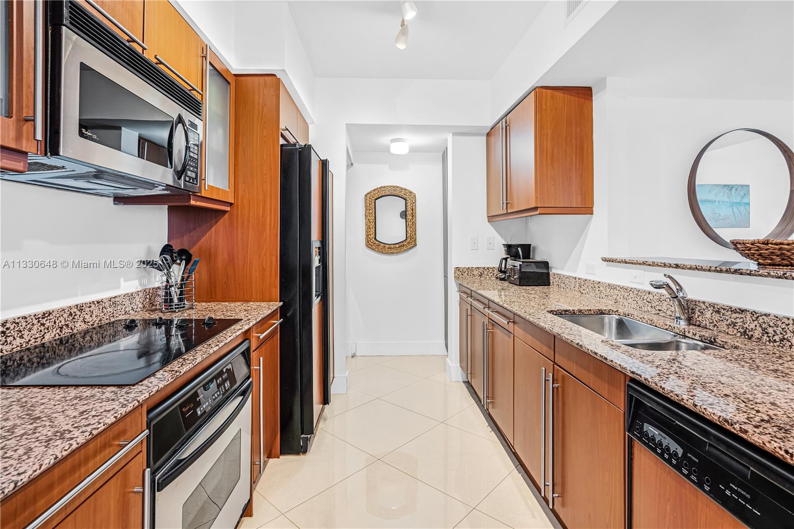 A galley kitchen features wood cabinets, granite countertops, stainless steel appliances, and tile flooring — 2080 S Ocean Dr,, Hallandale Beach FL 33009, HALLANDALE BEACH, FL