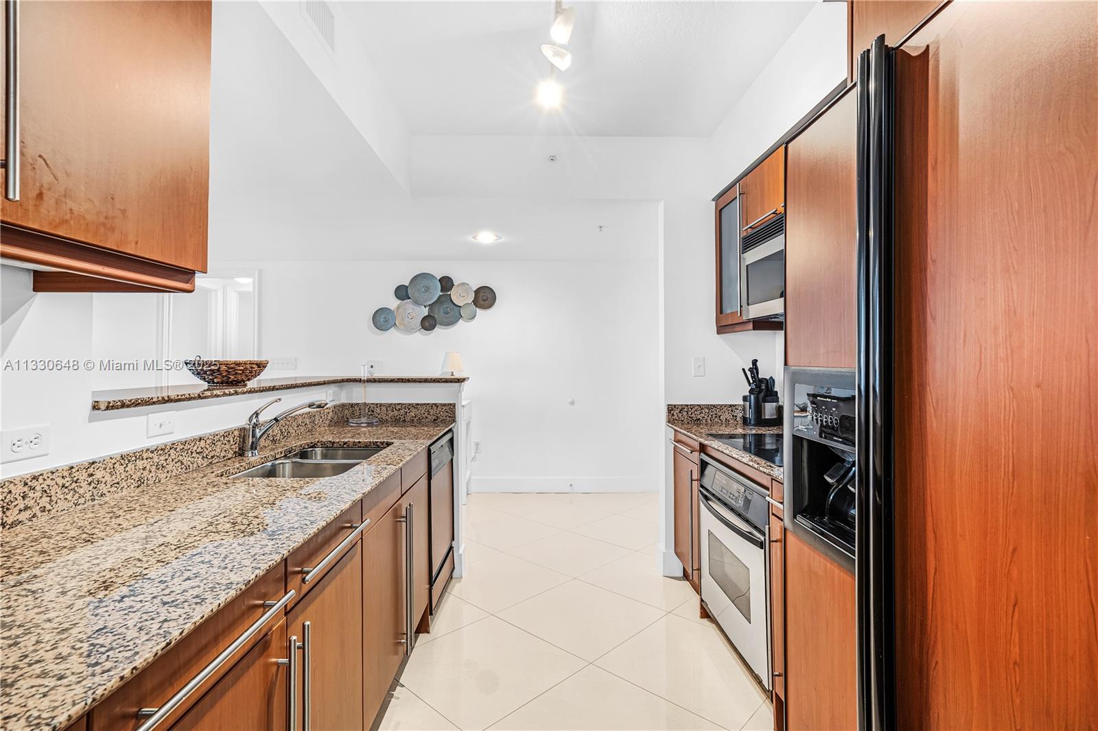 A galley-style kitchen features wood cabinets, granite countertops, and stainless steel appliances — 2080 S Ocean Dr,, Hallandale Beach FL 33009, HALLANDALE BEACH, FL