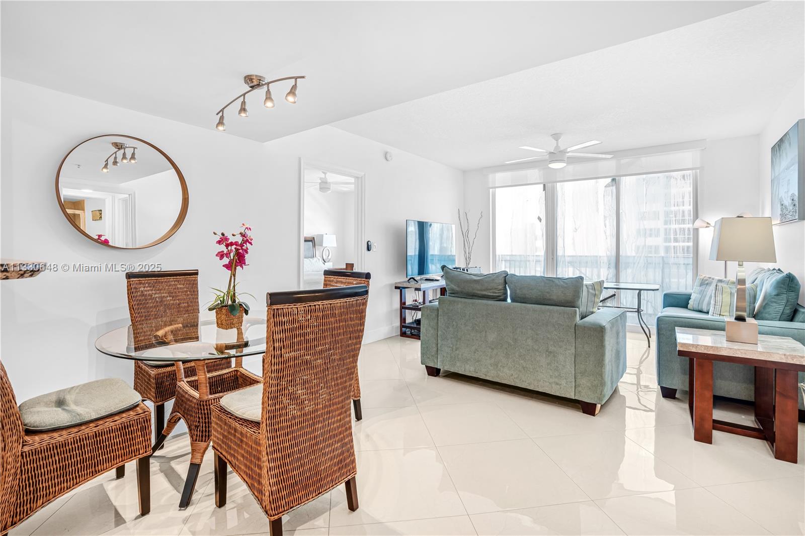 A bright living and dining area features white tile floors, wicker chairs, and blue furniture — 2080 S Ocean Dr,, Hallandale Beach FL 33009, HALLANDALE BEACH, FL