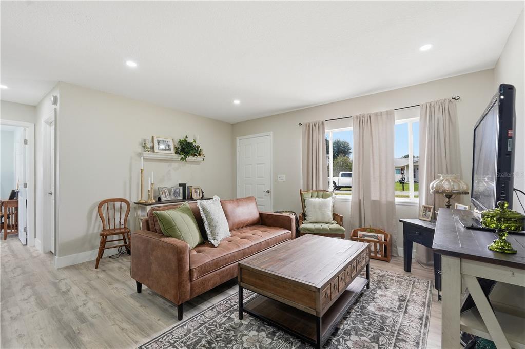 A living room features a brown leather sofa, wood coffee table, and light wood flooring — 11094 SW 79TH AVENUE, OCALA, FL