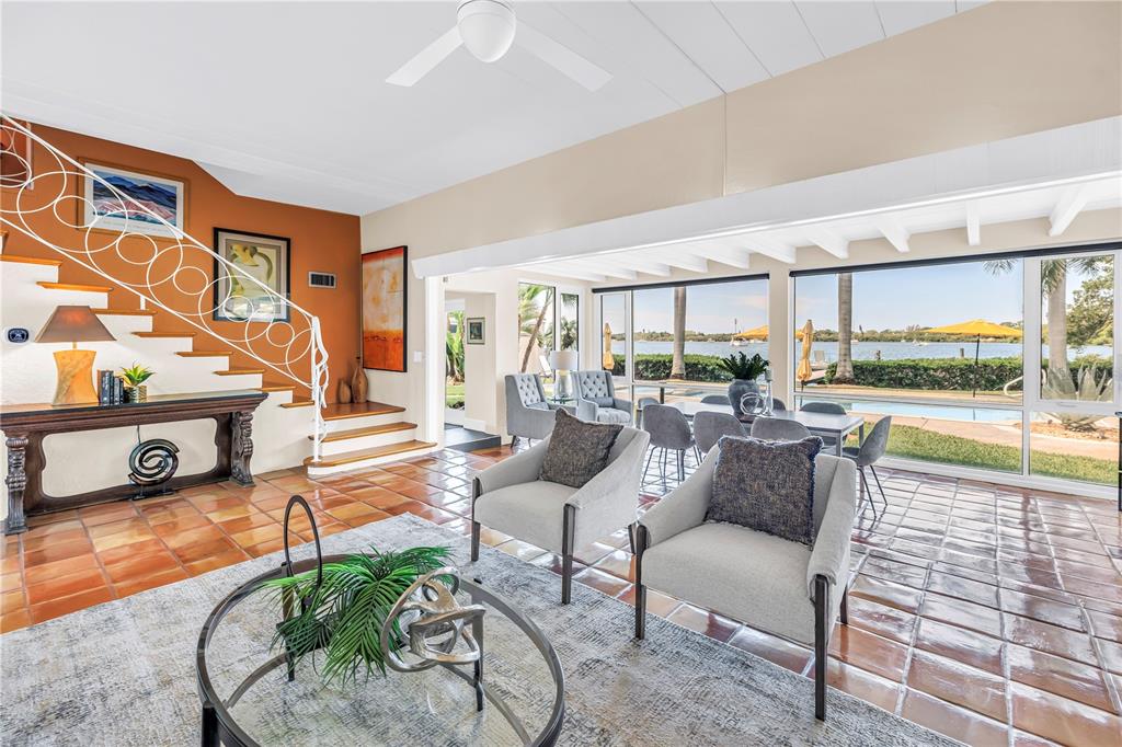 A living room with terracotta tile floors, a white staircase, and large windows overlooking water — 2781 BAYSIDE DRIVE S, ST PETERSBURG, FL