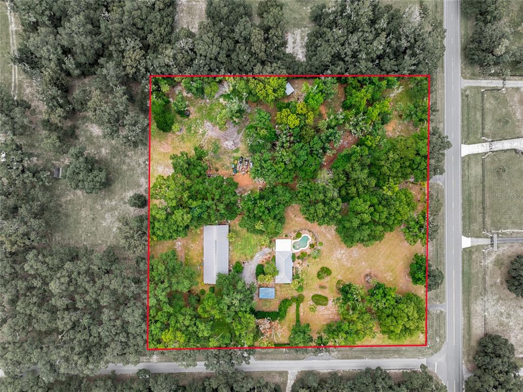 An aerial view shows a house with a pool on a large, tree-covered lot — 40847 COUNTY ROAD 439, UMATILLA, FL