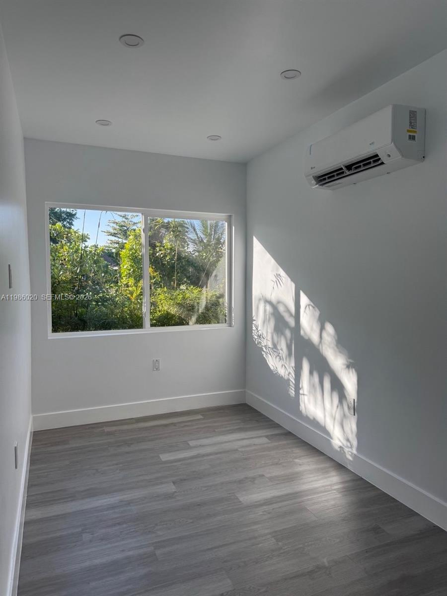 A small room with gray wood-look flooring, a window, and a wall-mounted air conditioning unit — 5800 SW 122nd Ave # 2, Miami FL 33183, MIAMI, FL
