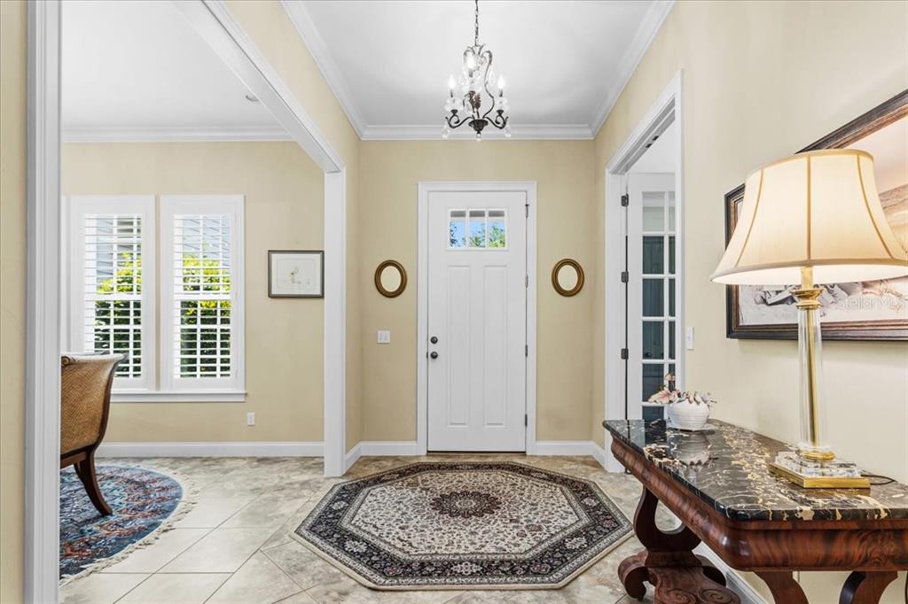 An entryway features tile flooring, an octagonal rug, a chandelier, and a white front door — 2772 NW 26TH PLACE, GAINESVILLE, FL