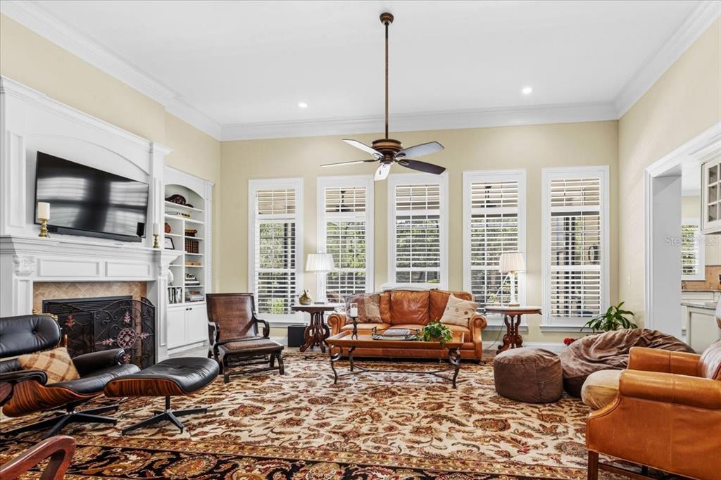 A living room features a fireplace, built-in shelves, a ceiling fan, and a patterned rug — 2772 NW 26TH PLACE, GAINESVILLE, FL