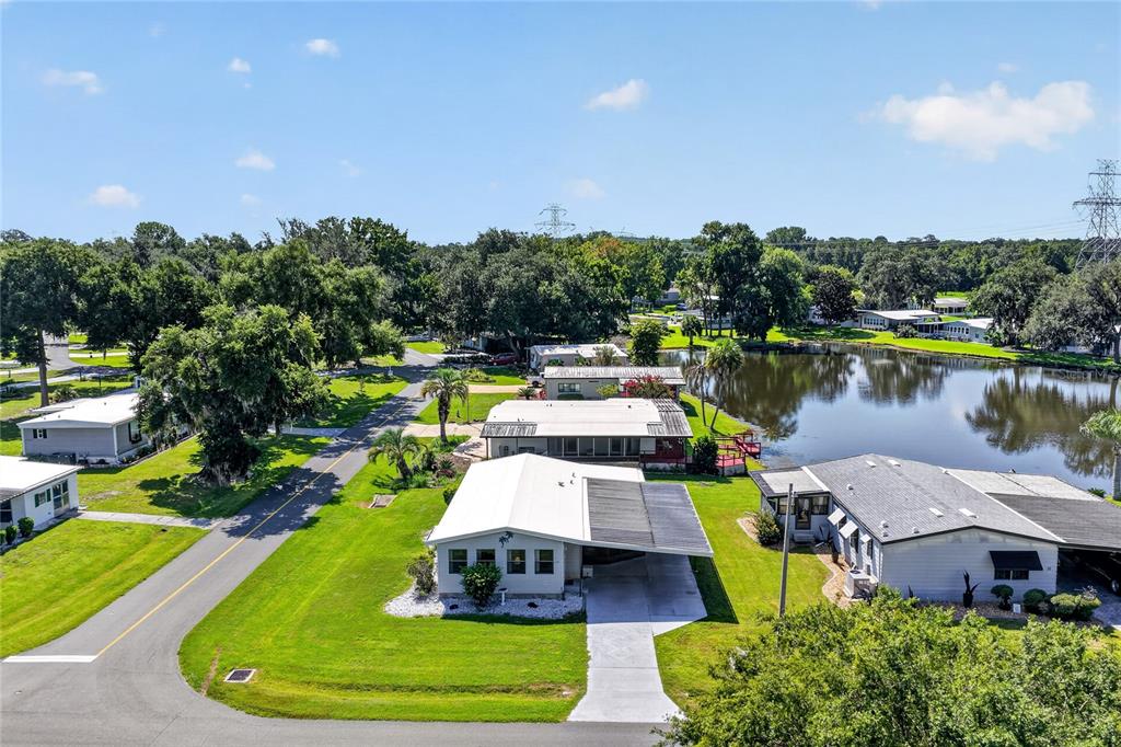 An aerial view shows several mobile homes situated near a pond and green trees — 12 N BOBWHITE ROAD, WILDWOOD, FL