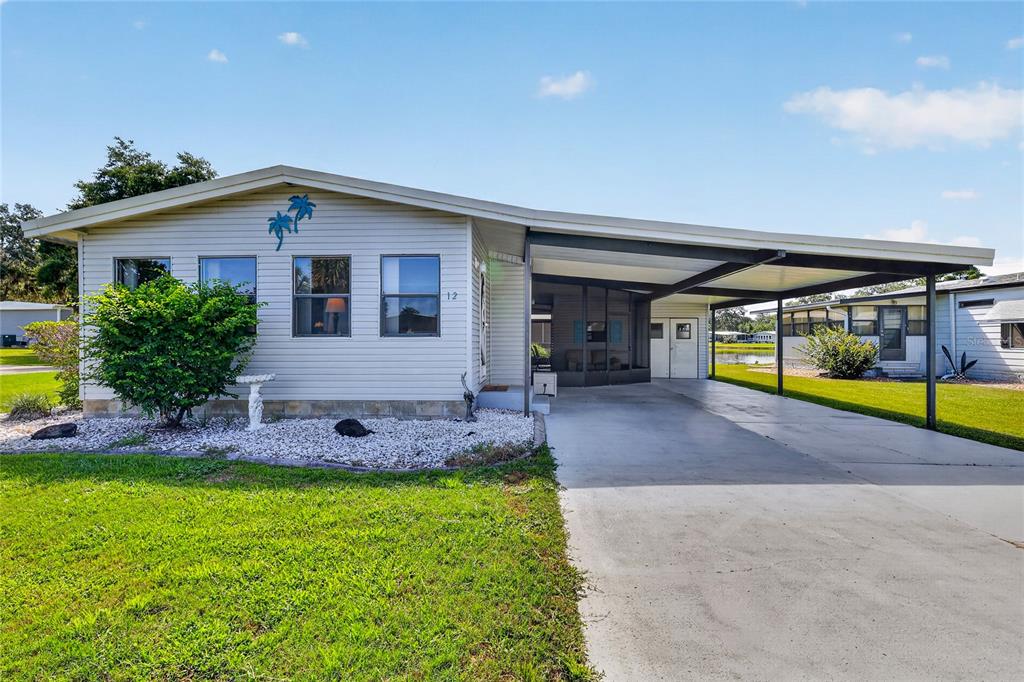 A single-story house with light siding, a carport, and a screened-in front porch — 12 N BOBWHITE ROAD, WILDWOOD, FL