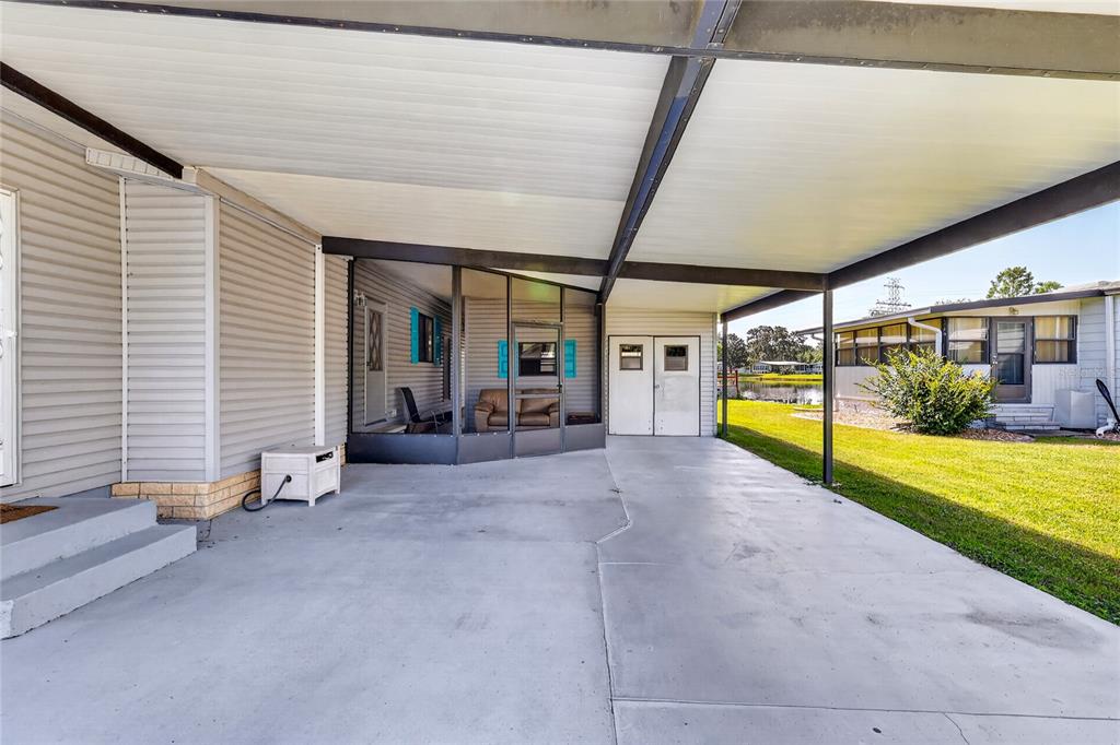 A concrete carport with a metal roof extends from the side of a mobile home — 12 N BOBWHITE ROAD, WILDWOOD, FL
