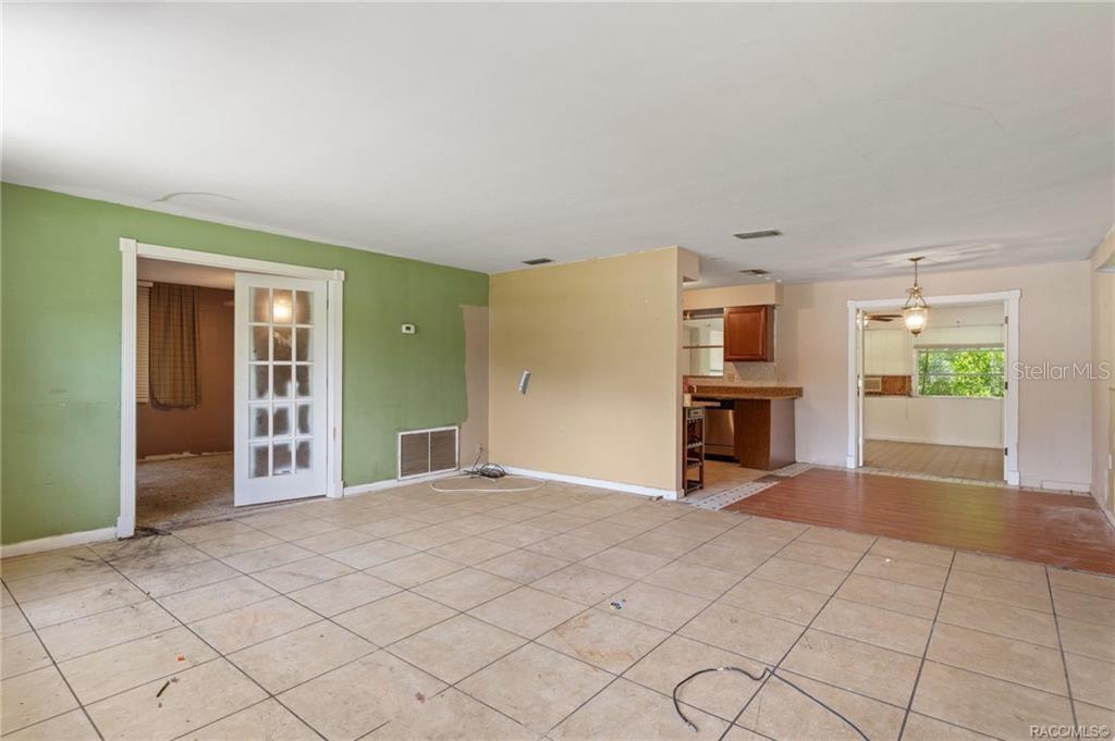 An interior view of a living room with tiled floors, green and tan walls, and doorways — 45 S BARBOUR STREET, BEVERLY HILLS, FL