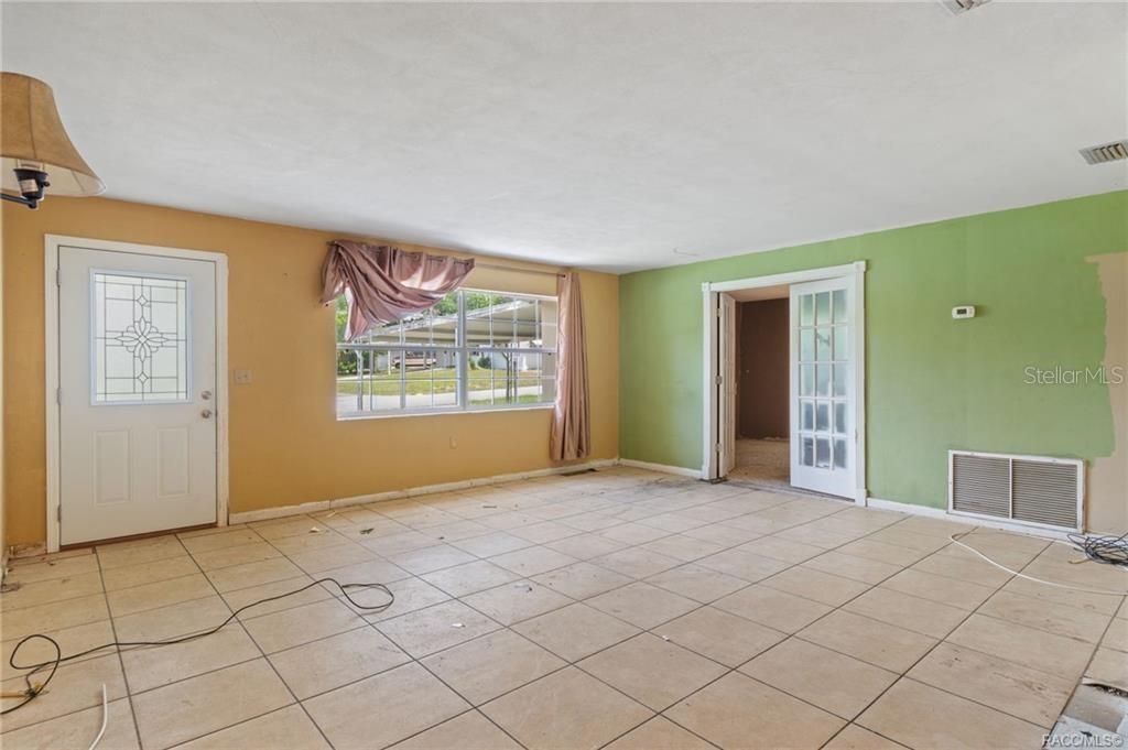 An empty room with tan and green walls, tile flooring, and a glass-paneled door — 45 S BARBOUR STREET, BEVERLY HILLS, FL