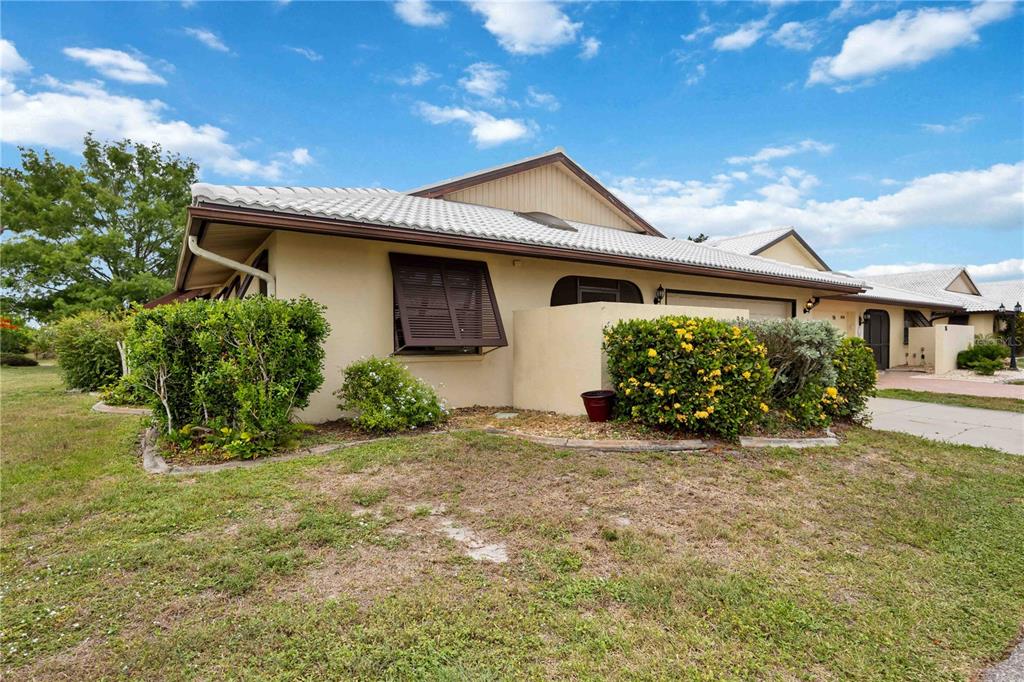 A single-story house with a light-colored exterior, a tiled roof, and a front garden — 98 DRIFTING SANDS DRIVE, VENICE, FL