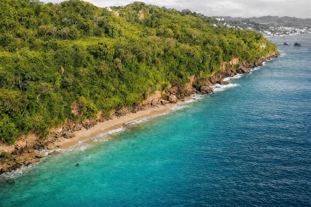 An aerial view of a lush, green hillside meeting a sandy beach and turquoise ocean — CARR 107 KM 1.1 BO BORINQUEN, AGUADILLA, PR
