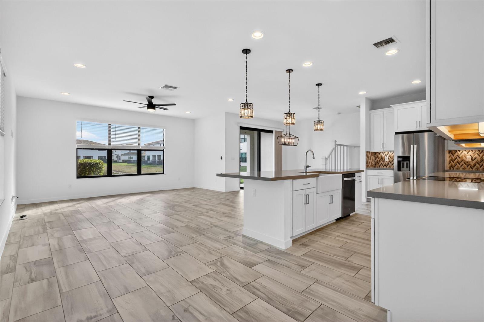 An open-concept kitchen and living area features white cabinetry, a central island, and tile flooring — 8792 Antarus Drive, Lake Worth FL 33467, LAKE WORTH, FL