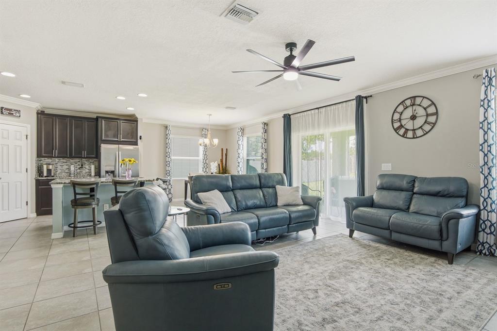 A living room with blue leather furniture, tile floors, and an open kitchen — 18793 DEER TRACKS LOOP, LUTZ, FL