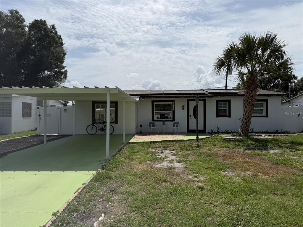 A single-story house with a carport, solar panels, and a palm tree in the yard — 4519 EDEN ROCK ROAD, TAMPA, FL