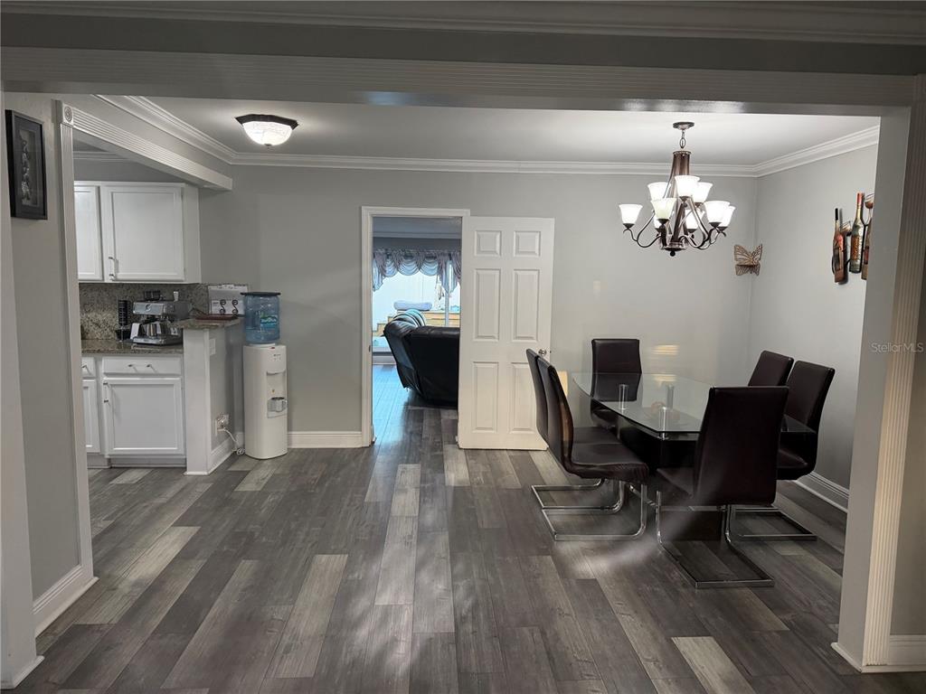A dining area with a glass table and chairs adjacent to a kitchen with white cabinets — 4519 EDEN ROCK ROAD, TAMPA, FL