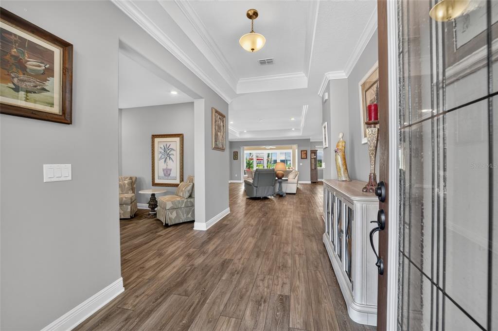 A view from an entryway into a living room with wood-look flooring and tray ceilings — 8370 SW 99TH TERRACE, OCALA, FL