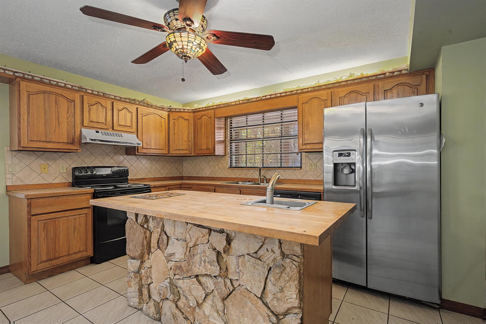 A kitchen features wood cabinets, a stone-base island with a butcher block top, and appliances — 665 Moon Ranch Road, Sebring FL 33870, SEBRING, FL
