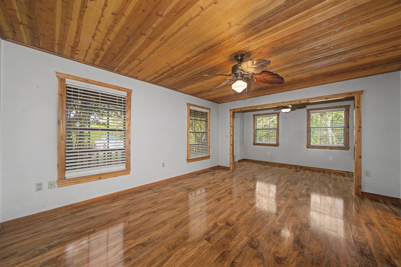 An empty living room features a wood-paneled ceiling, hardwood flooring, and multiple windows — 665 Moon Ranch Road, Sebring FL 33870, SEBRING, FL