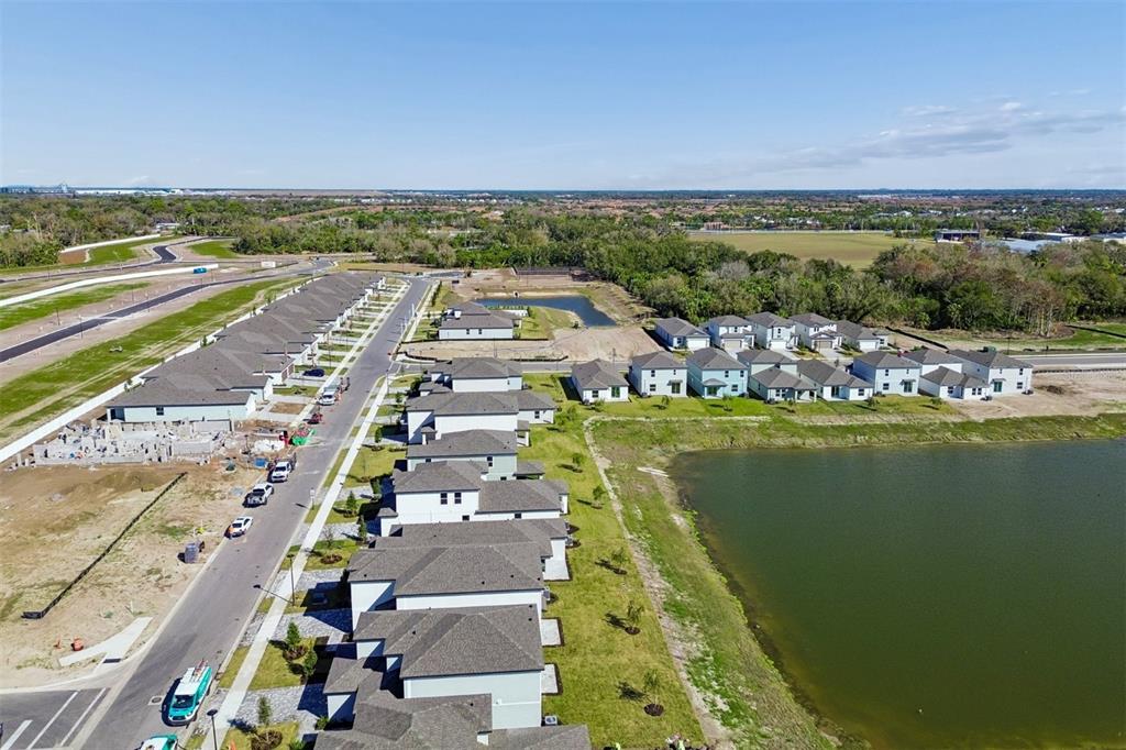 An aerial view shows a suburban neighborhood with newly constructed houses and a large pond — 9018 OPTIMIST WAY, PALMETTO, FL