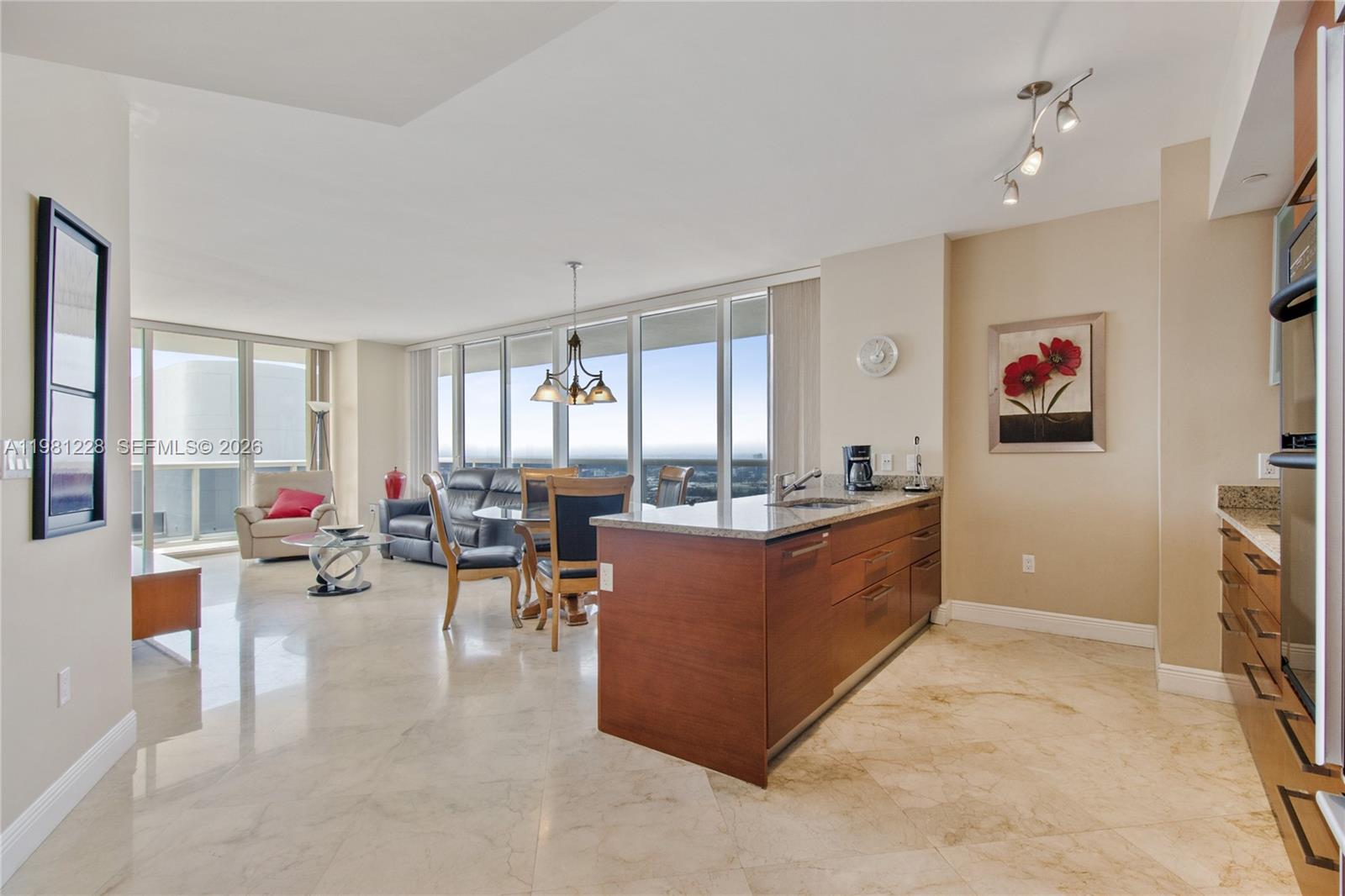 An open-concept kitchen and living area features marble floors, wood cabinetry, and floor-to-ceiling windows — 1830 S Ocean Dr # 4606, Hallandale Beach FL 33009, HALLANDALE BEACH, FL