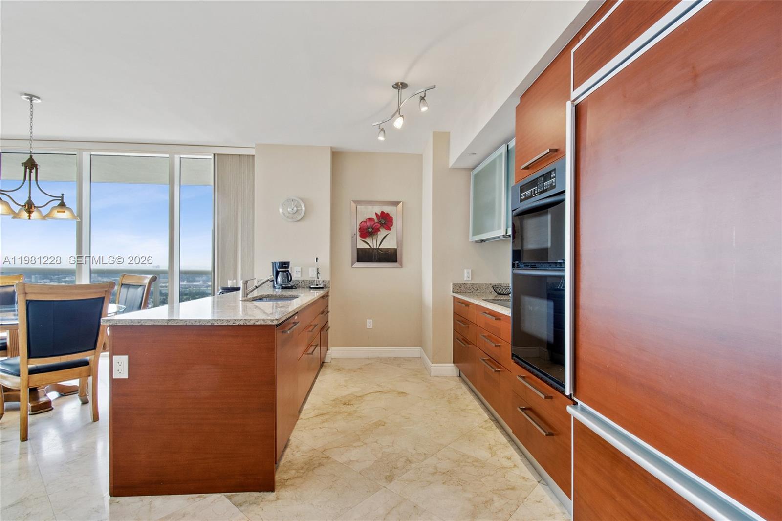 A modern kitchen features wood cabinetry, granite countertops, stainless steel appliances, and tile flooring — 1830 S Ocean Dr # 4606, Hallandale Beach FL 33009, HALLANDALE BEACH, FL