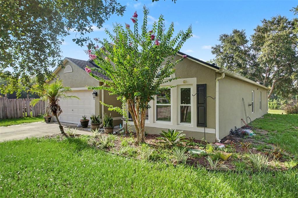 A single-story house with a tan stucco exterior, a two-car garage, and a landscaped yard — 9450 WATER ORCHID AVE, CLERMONT, FL