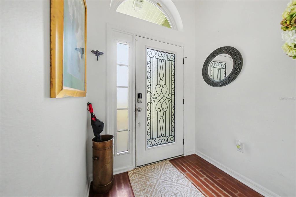 An entryway features a white door with decorative glass, a side window, and wood flooring — 9450 WATER ORCHID AVE, CLERMONT, FL