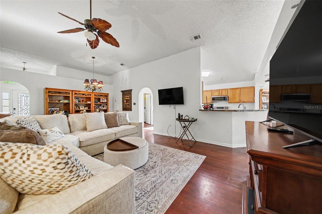 A living room features a sectional sofa, a patterned rug, and an open kitchen — 9450 WATER ORCHID AVE, CLERMONT, FL