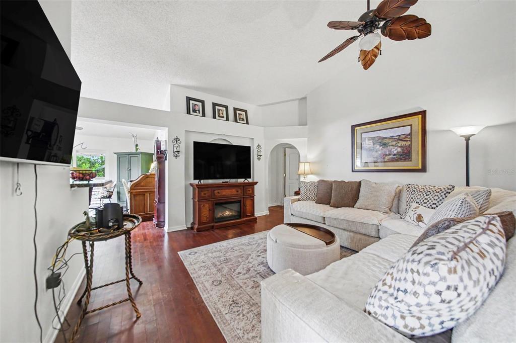 A living room features a sectional sofa, a fireplace with a television, and hardwood floors — 9450 WATER ORCHID AVE, CLERMONT, FL